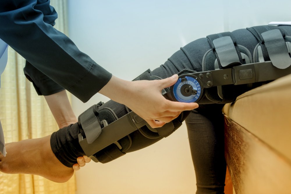 Physiotherapist adjusting a patient's knee braces